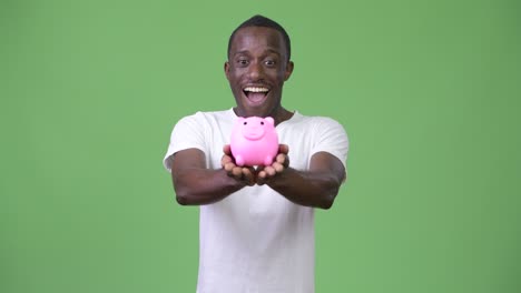 young african man holding piggy bank