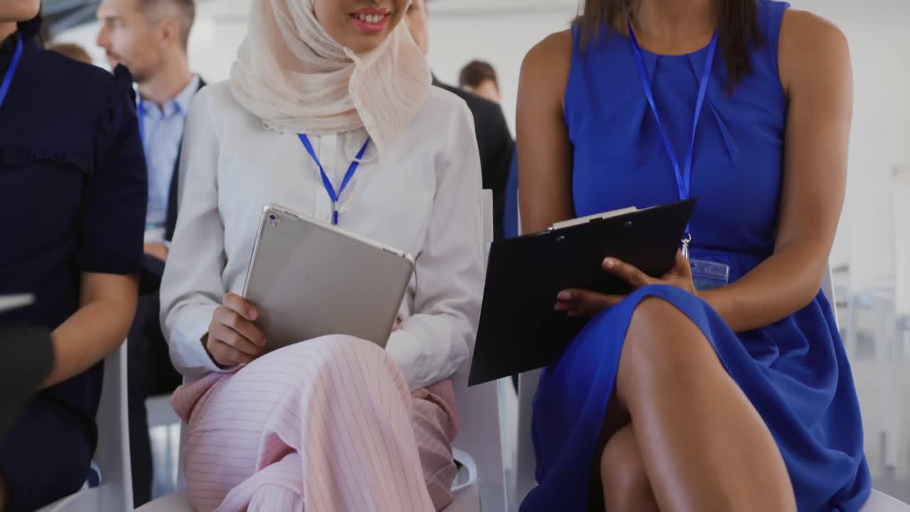Women in the audience at a business seminar writing