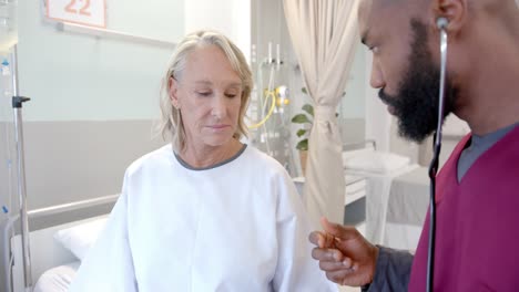 african american male doctor with stethoscope examining caucasian female patient at hospital