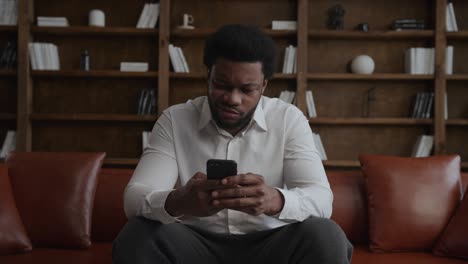 young adult african american man is unhappy about price while online shopping on his smartphone