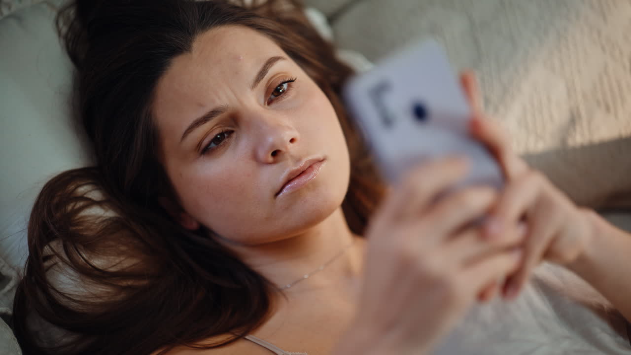 Waking woman checking smartphone receiving message early morning at home closeup