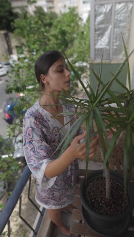 woman caring for a plant on a balcony