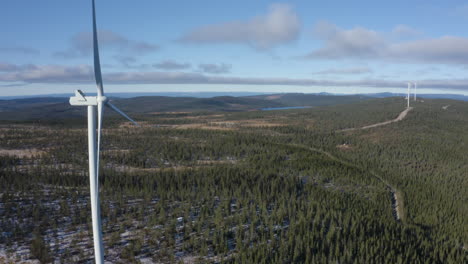 Wind farm with towering turbines in a vast, snow-dusted forest landscape