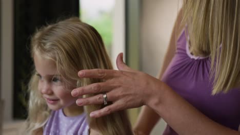 mother brushing the hair on her daughter