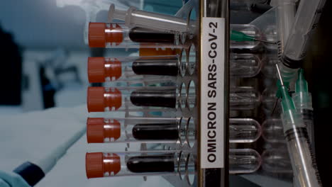 a close up vertical video of medical samples labelled omicron b.1.1.529 being placed in to a laboratory rack at a research facility, the new strain of carona virus