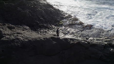 一名年轻女子沿着海岸行走,可以看到海浪的空中拍摄