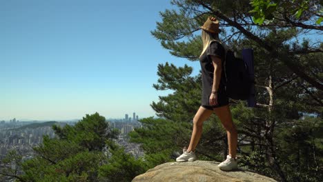 girl standing on the boulders and looking at the scenic downtown skyline in seocho-gu district from gwanaksan mountain in seoul, south korea