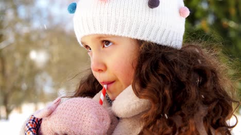 Niña-Bebiendo-Té-Caliente-Durante-Una-Caminata-En-Invierno.-Toma-Aérea-En-ángulo-Bajo-De-Una-Linda-Niña-Con-Gorro,-Parka-Y-Guantes-Bebiendo-Té-Caliente-De-Una-Taza-De-Acero-Inoxidable-Mientras-Camina-Por-El-Bosque-En-Un-Día-Soleado-De-Invierno.