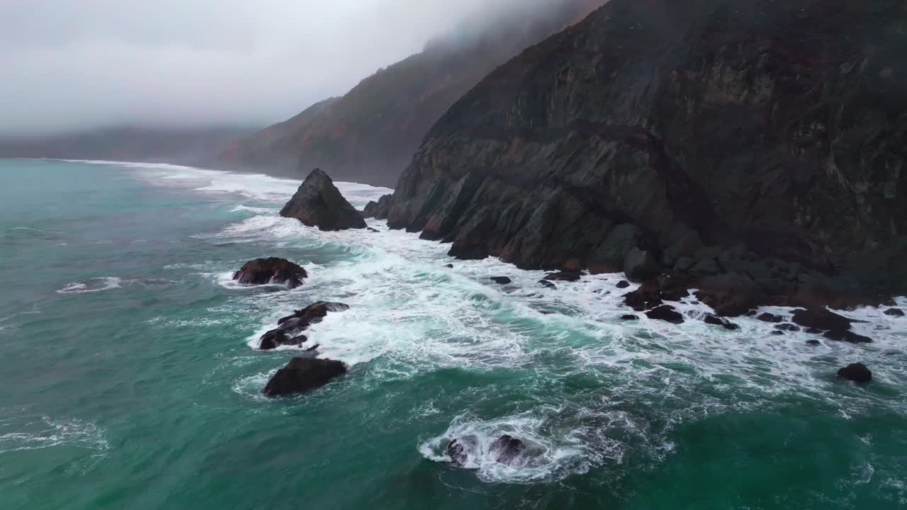 Rugged dramatic untouched coastline USAL Beach campground cloud layer mist rain fog aerial drone California PNW Lost Coast Trail morning huge surf waves boulder rocks nature landscape backwards pan up