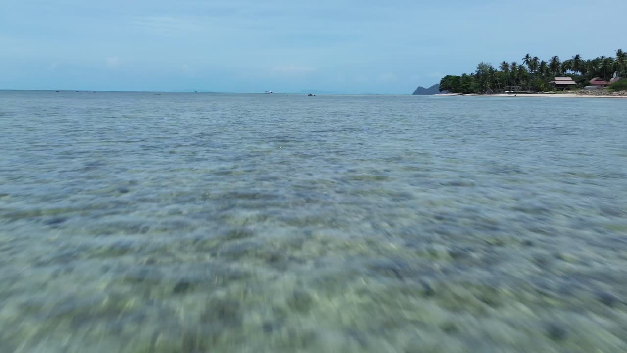 Aerial footage of Thong Sala Beach with a wide sandy shoreline, turquoise sea and lush tropical scenery on Koh Phangan island, Thailand