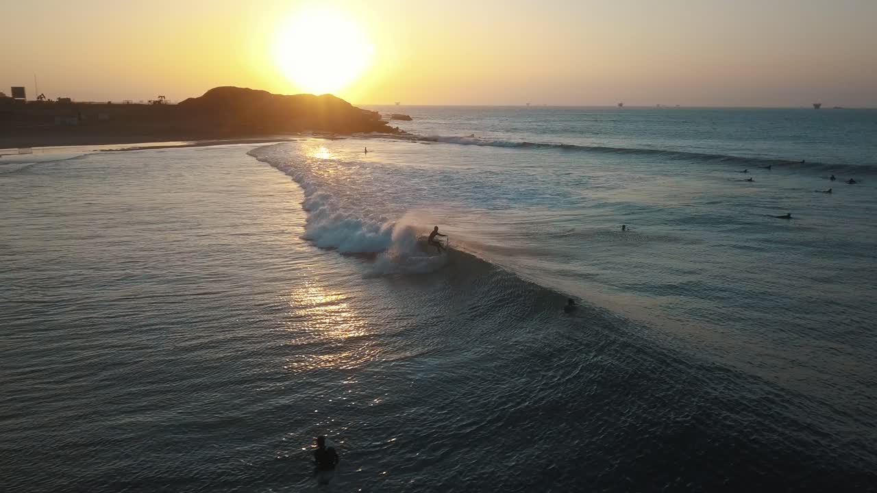 Drone Aerial tracking a pro surfer, during sunset, at the coast of Talara, in Peru - tracking, drone shot