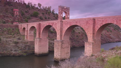 cinematic wide tracking shot of alcántara bridge at sunset