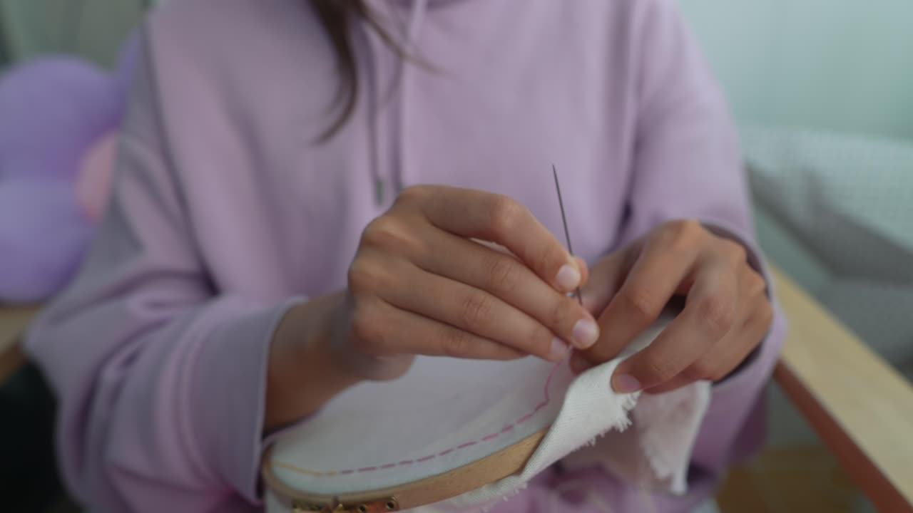 Primo piano di mani che ricamano un tessuto con ago e filo