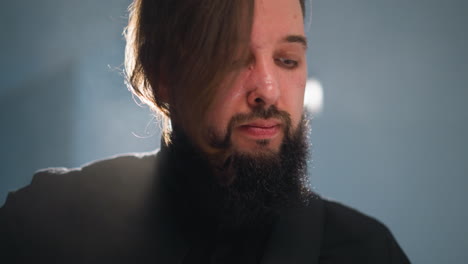 intense close-up of a bearded man in a black shirt, emotionally engaging, with a blurred background