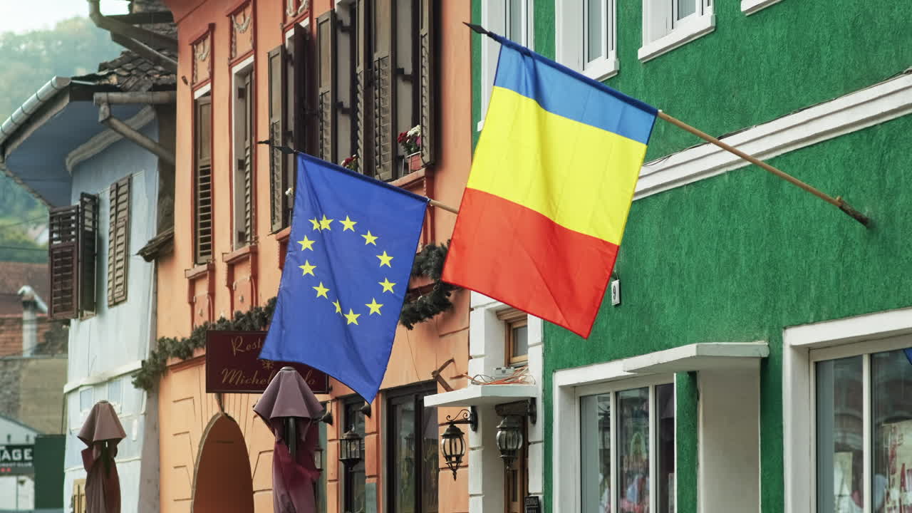SIGHISOARA, ROMANIA - OCTOBER 9, 2021: Romanian and European flags on a facade of a building in Romania