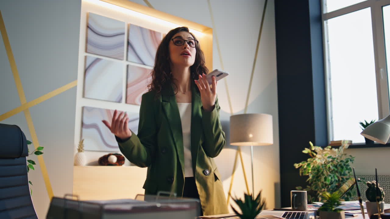 una mujer joven llamando al altavoz en la oficina. una chica gerente grabando un mensaje de voz.