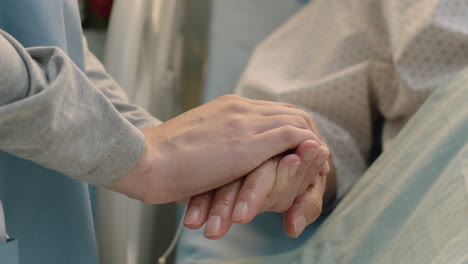 hospital nurse holding hand of old woman in bed comforting elderly patient hospitilized recovering from illness medical professional at bedside giving encouragement health care support