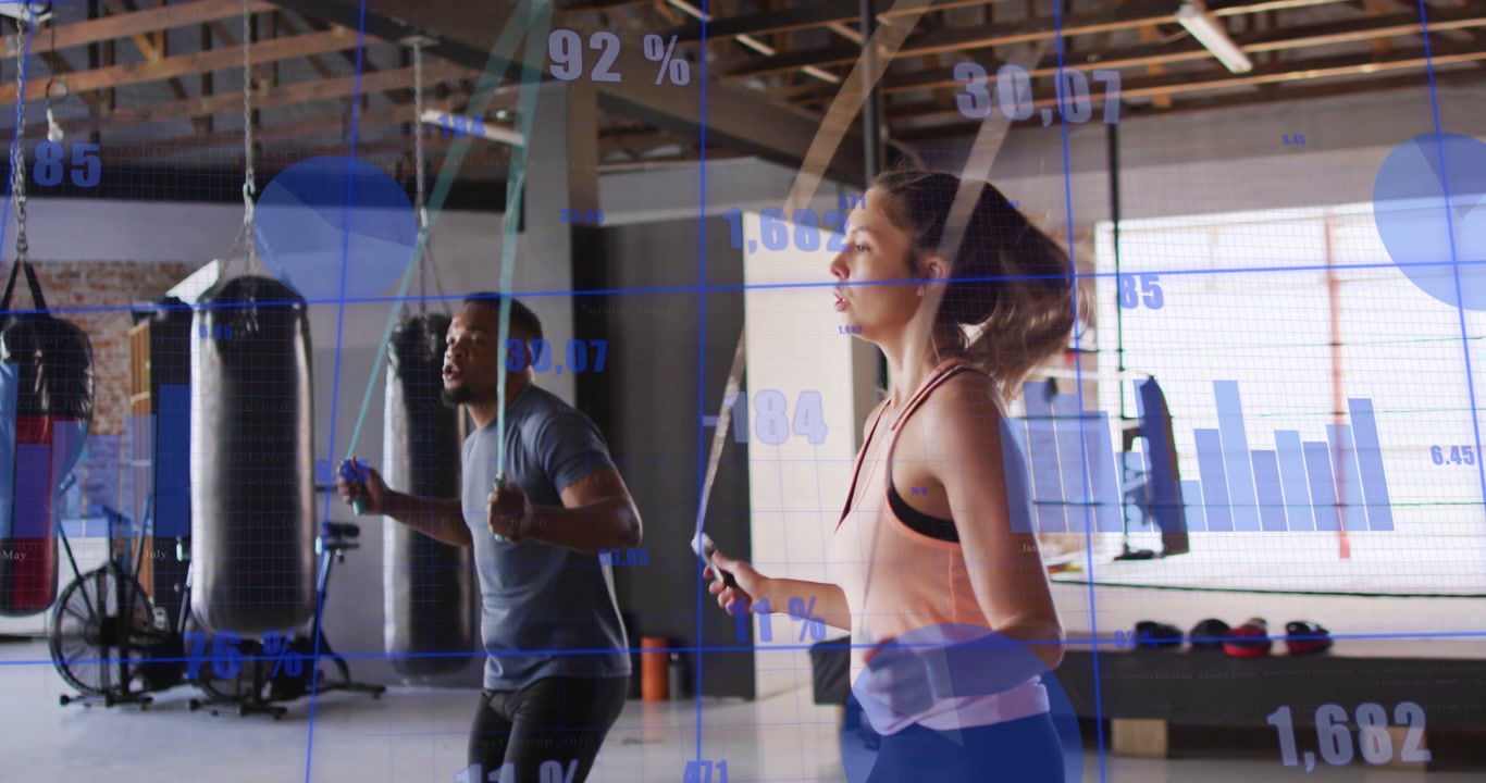 Man and woman starting skipping for cardio in gym, blue overlay charts tracking metrics