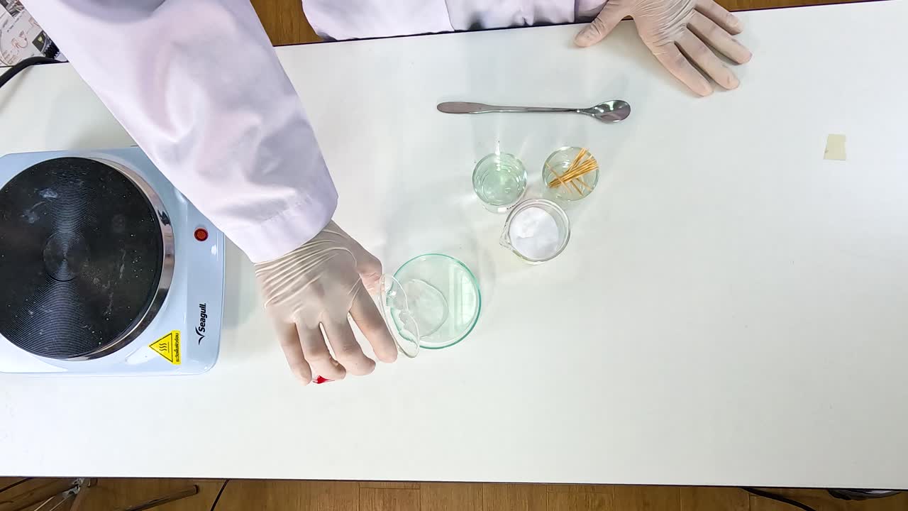 A laboratory experiment demonstrating sodium acetate crystallization with precise movements and clear lighting, highlighting scientific procedures