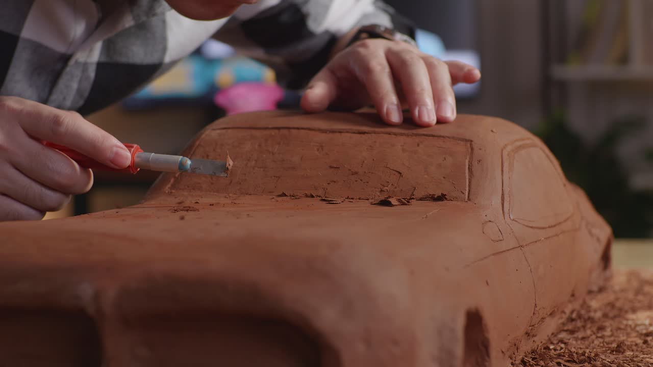 Close Up Of Man Automotive Designer'S Hands Using Rake Or Wire To Create Details In The Sculpture Of Car Clay In The Studio
