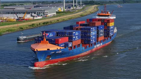 cargo ship laden with containers sailing in the river, filmed by a drone