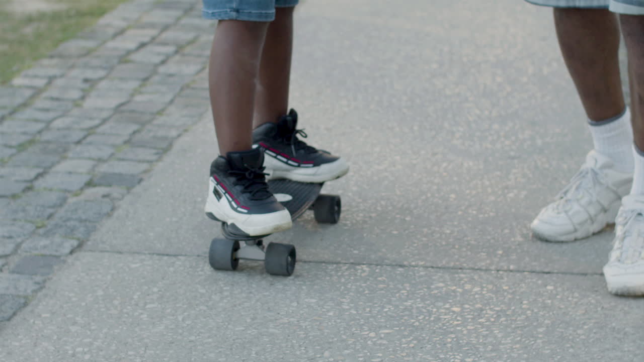Father helping his son in learning skateboarding outdoors.