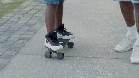 Father-helping-his-son-in-learning-skateboarding-outdoors.