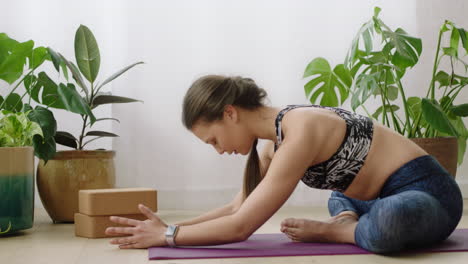 atractiva mujer de yoga ejerciendo un estilo de vida saludable practicando la pose de loto hacia adelante disfrutando del entrenamiento en casa entrenando en una colchoneta de ejercicios