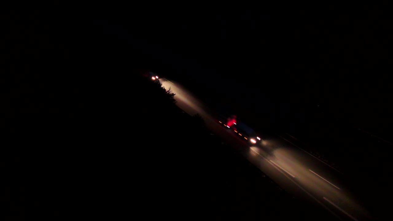 White xenon headlights and red backlights of cars or vehicles on motorway at night. Aerial top down shot. Traffic scene on American interstate highway