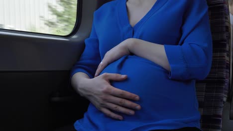 mujer embarazada viaja en tren mientras se frota el vientre