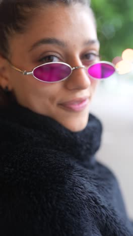 young woman in pink sunglasses and black turtleneck