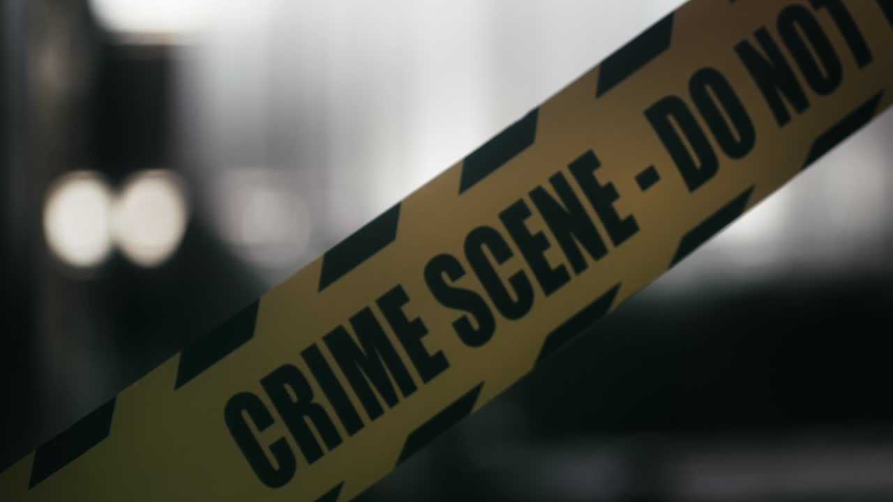 CRIME SCENE - DO NOT CROSS” tape in focus against a blurred interior background, creating a somber and intense mood typical of crime scenes