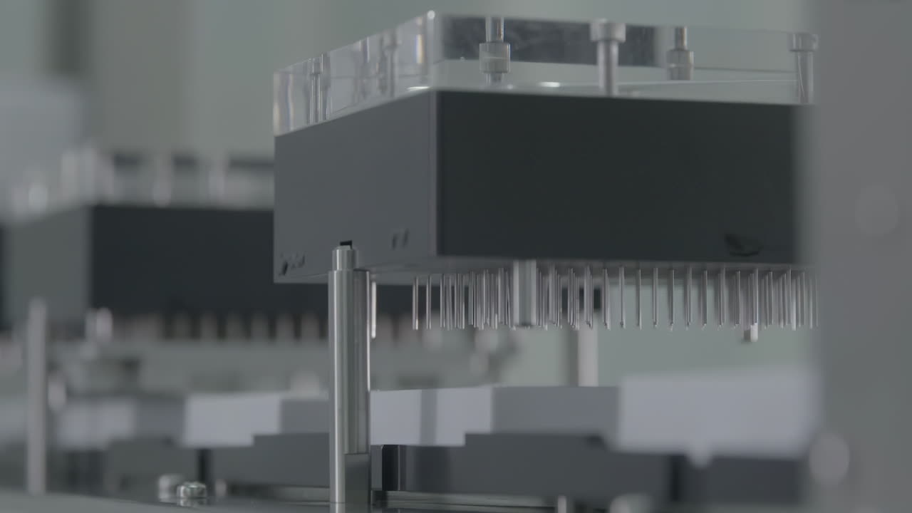 High-tech automated pharmaceutical production line filling glass vaccine vials with liquid medicine in a sterile drug factory manufacturing environment setting.