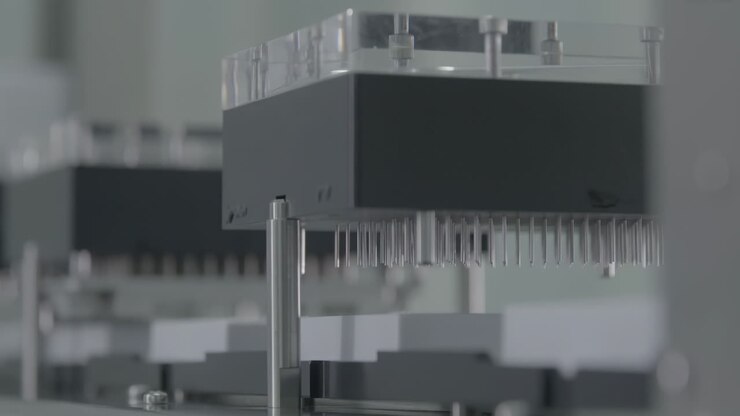 High-tech automated pharmaceutical production line filling glass vaccine vials with liquid medicine in a sterile drug factory manufacturing environment setting.