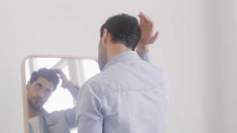 good looking man touching his hair in front of the mirror