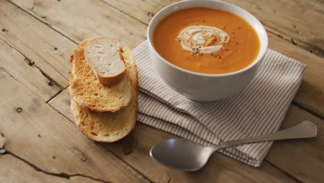 Vídeo-De-Sopa-De-Tomate-Crema-En-Un-Tazón-Sobre-Una-Mesa-De-Madera-Con-Pan