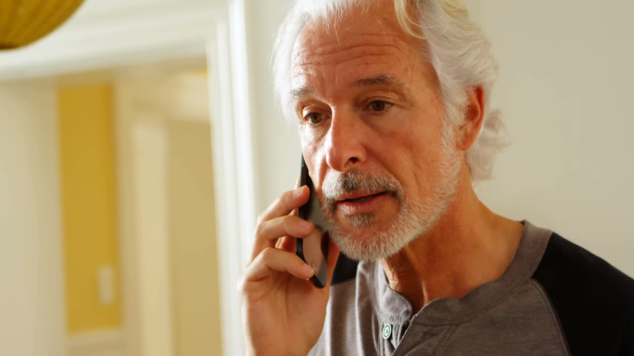 Senior man talking on mobile phone at home 4k