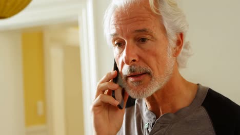 hombre mayor hablando por teléfono móvil en casa 4k