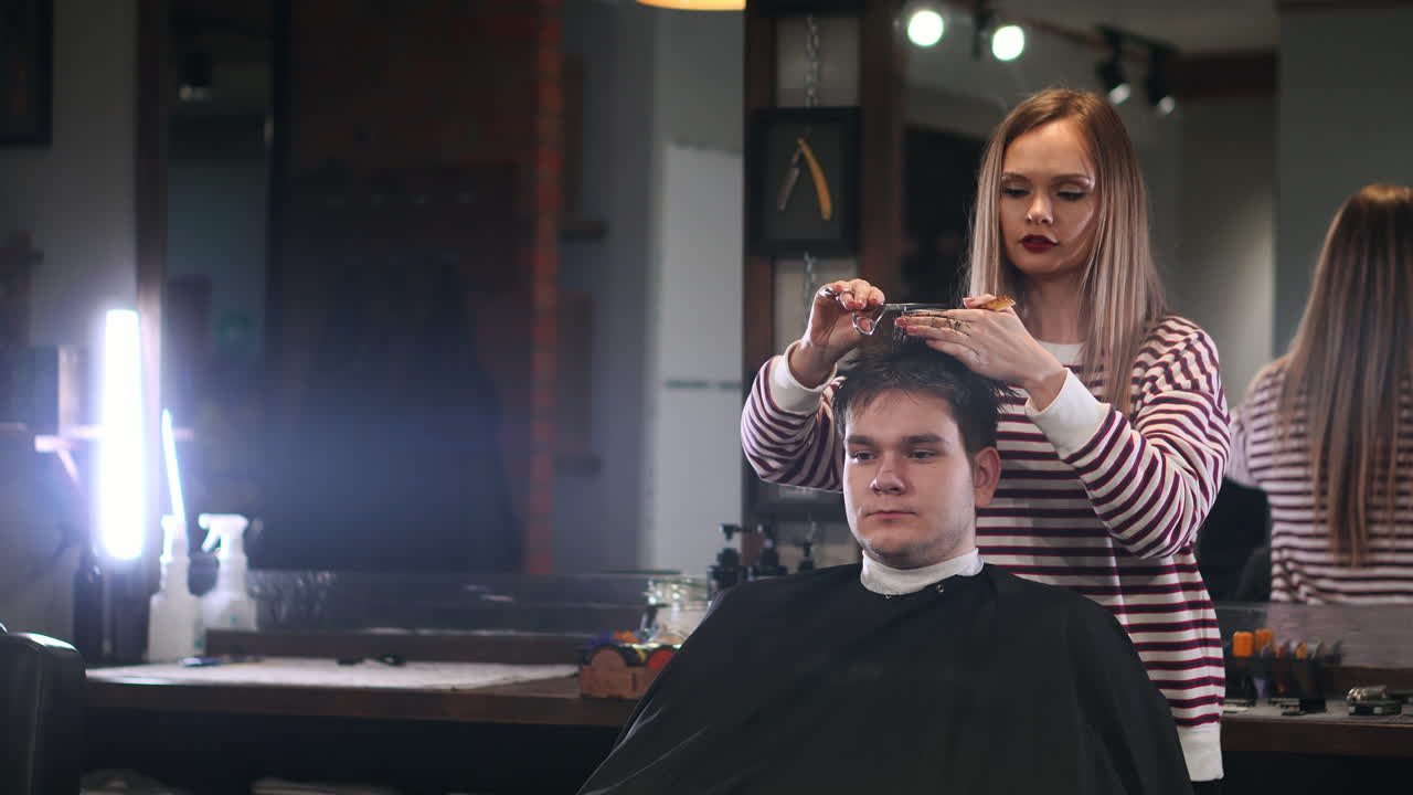 Men's hair salon, the girl makes a haircut scissors in a brutal interior.