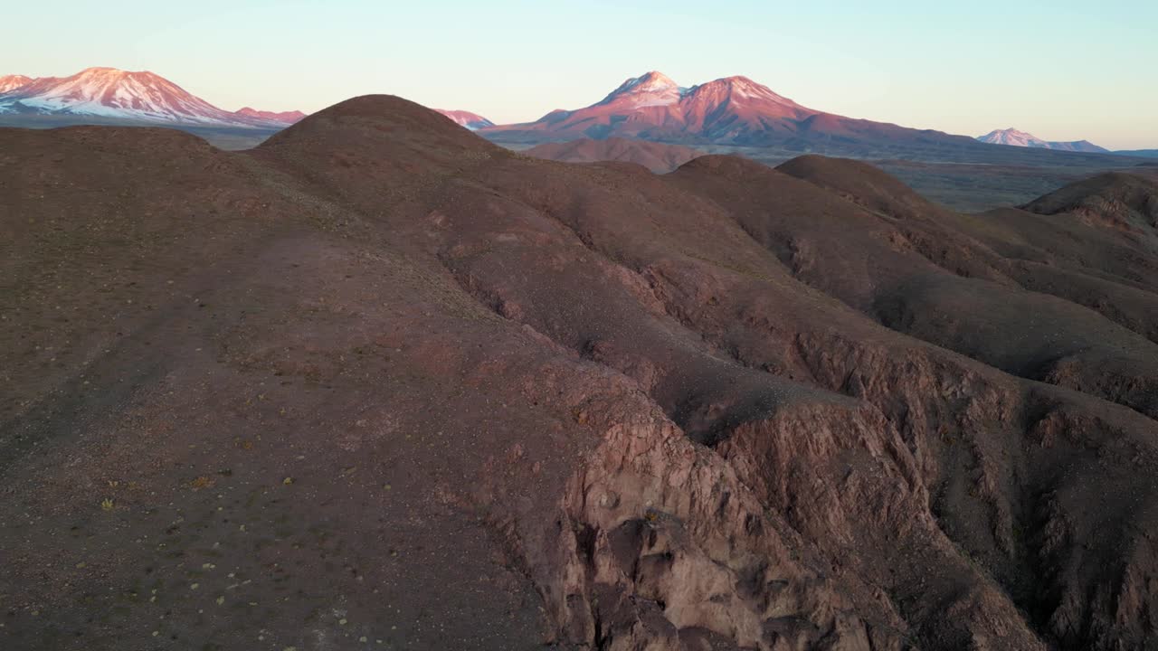 High-altitude drone footage capturing golden light on rugged desert peaks in the Andes