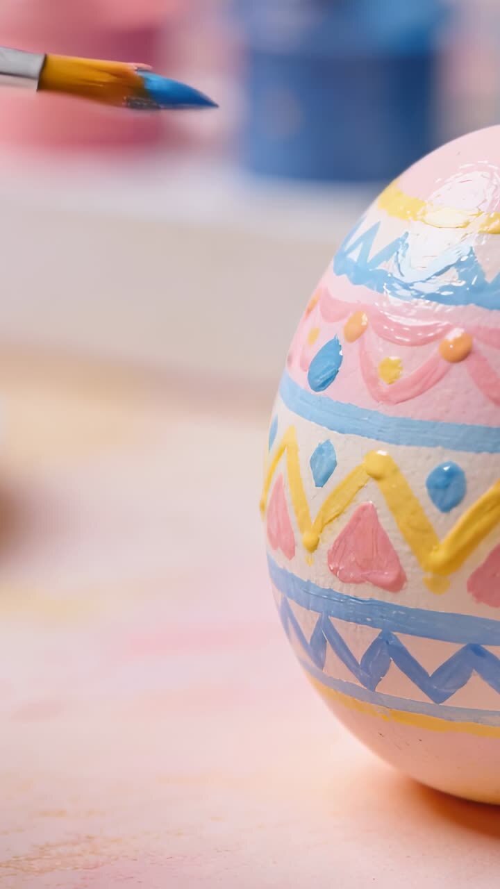 Close-up of a Paintbrush Decorating an Easter Egg with Colorful Patterns