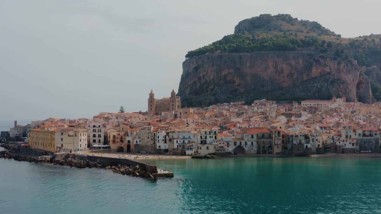 세팔루 해변의 공중 풍경: 해안가를 따라 으로 날아가는 드론 ; 시칠리아의 지중해에 있는 팔레르모 시 근처의 작은 역사적인 마을; 매력적인 이탈리아 마을.