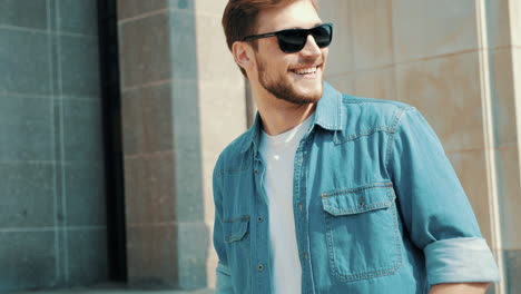 hombre sonriente con camisa de vaqueros y gafas de sol al aire libre