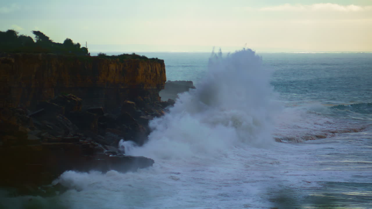 olas impresionantes chocando contra la costa rocosa al anochecer. océano tormentoso haciendo explosión