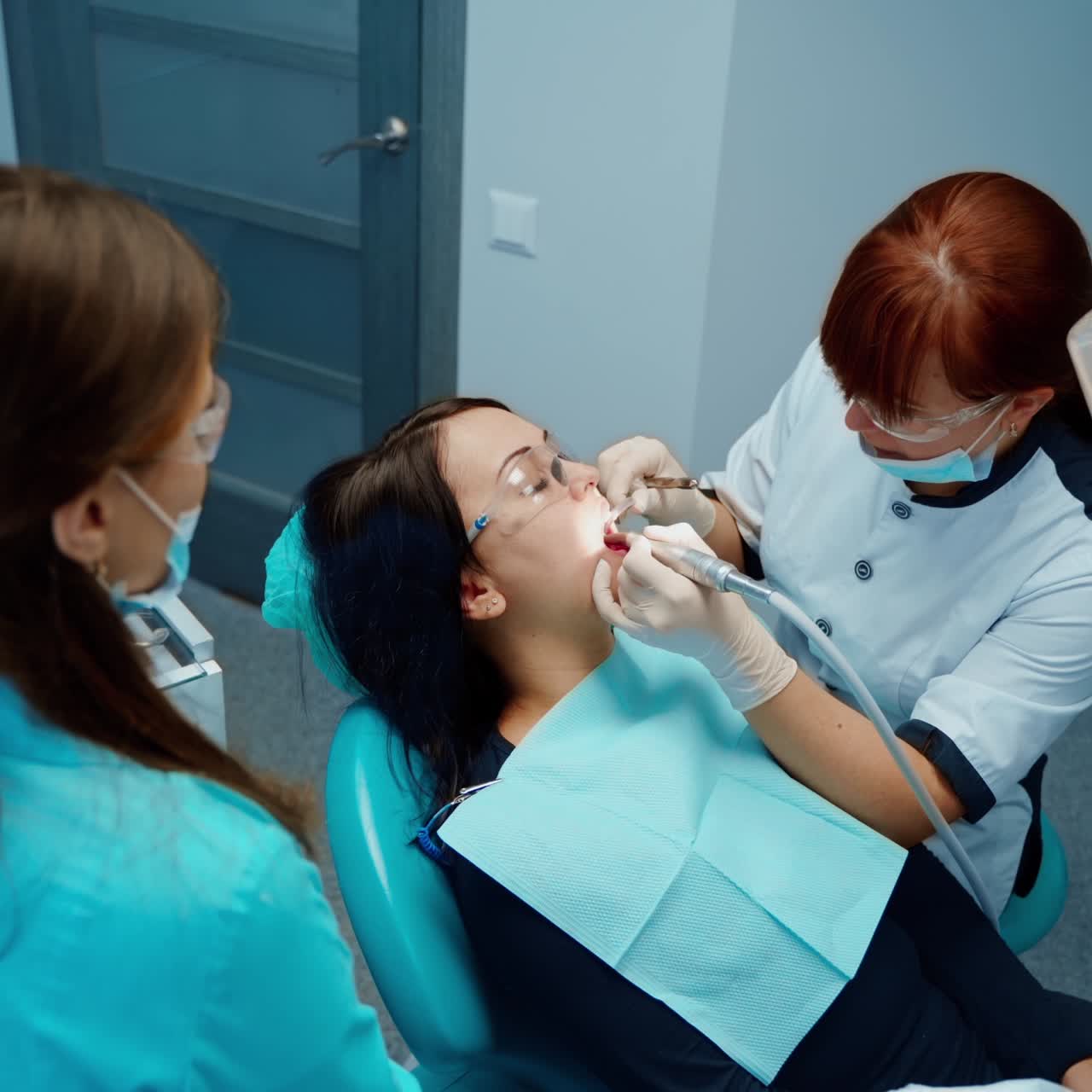 Female dentist and a client in dental chair. Professional stomatologist and assistant treating patient's tooth in a dental office. Top view.