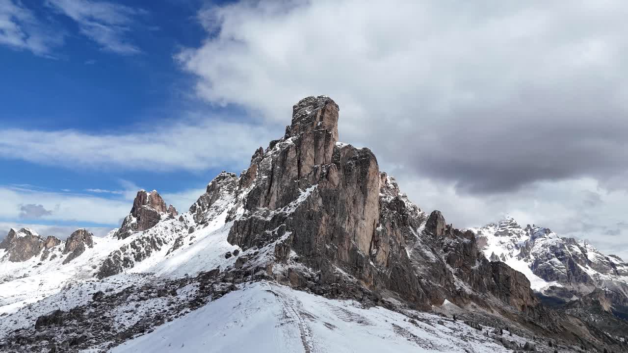 Drone pullback revealing Ra Gusela peak and snowy landscape near Passo Giau in the Dolomites