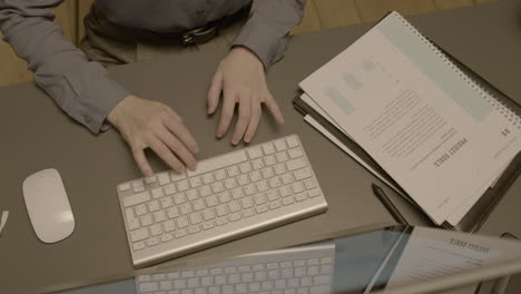 top view of unrecognizable female employee hands typing on laptop keyboard at workplace