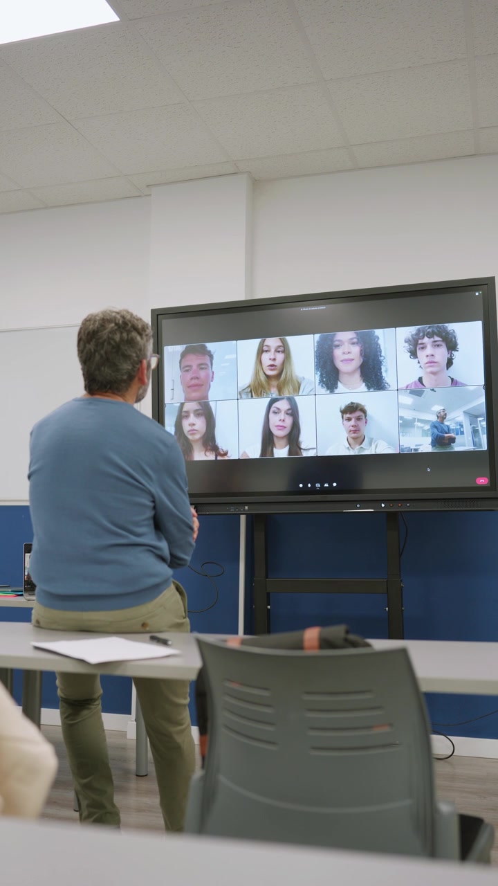 Insegnante che conduce una lezione virtuale con studenti su un grande schermo interattivo