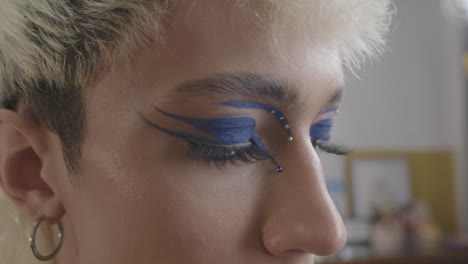 fotografía de cerca de una mujer joven usando delineador de ojos para crear un aspecto creativo de maquillaje púrpura