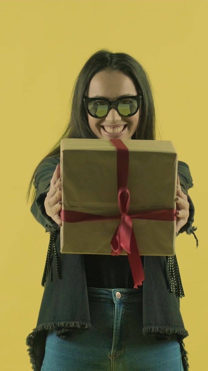 Giovane donna sorridente che porge una scatola regalo